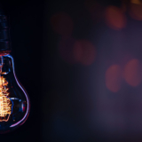 A burning lamp hangs in the dark on a blurred background. Space for text. High quality photo. A light bulb glows in the dark.